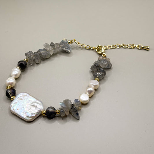 „Bransoletka Moonshield z labradorytu i pereł barokowych na złotych akcentach”

„Delikatna bransoletka z labradorytu i naturalnych pereł – biżuteria premium”

„Zbliżenie bransoletki Moonshield z szarego labradorytu i perły barokowej”