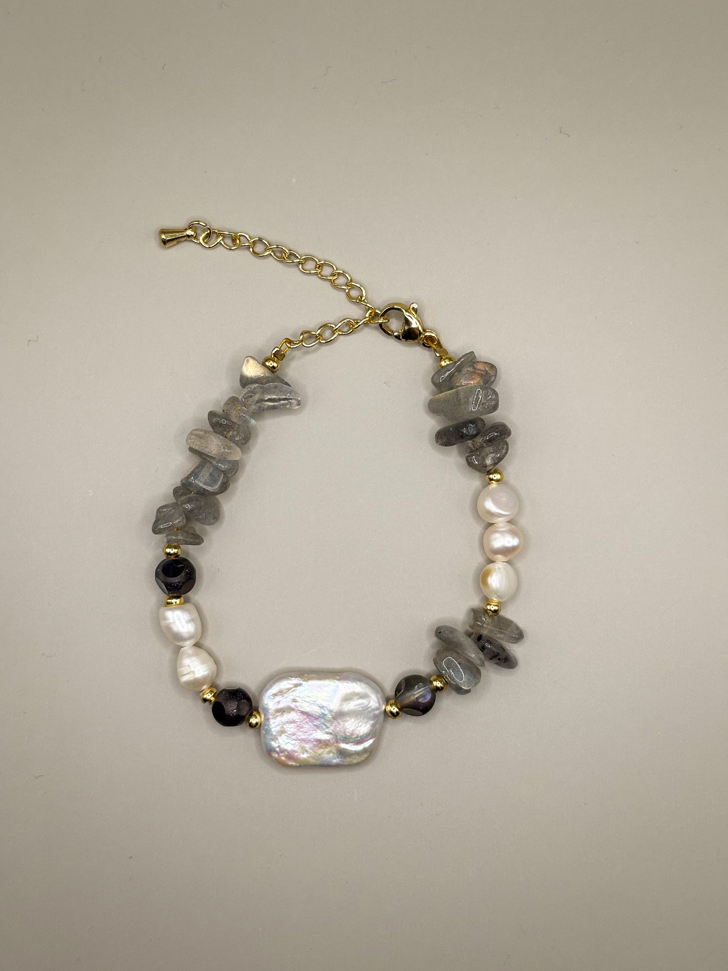 „Bransoletka Moonshield z labradorytu i pereł barokowych na złotych akcentach”

„Delikatna bransoletka z labradorytu i naturalnych pereł – biżuteria premium”

„Zbliżenie bransoletki Moonshield z szarego labradorytu i perły barokowej”