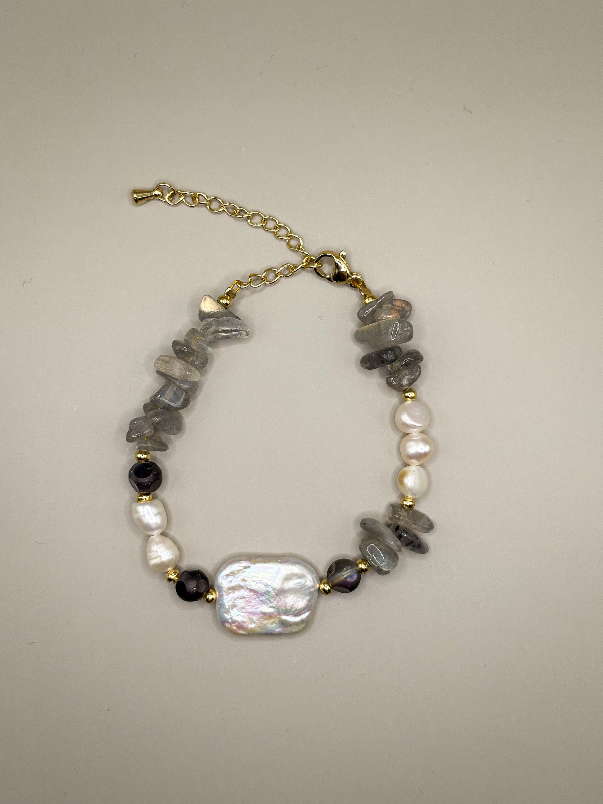 „Bransoletka Moonshield z labradorytu i pereł barokowych na złotych akcentach”

„Delikatna bransoletka z labradorytu i naturalnych pereł – biżuteria premium”

„Zbliżenie bransoletki Moonshield z szarego labradorytu i perły barokowej”